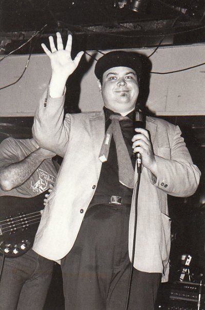 David Thomas onstage, waving and looking unusually cheerful