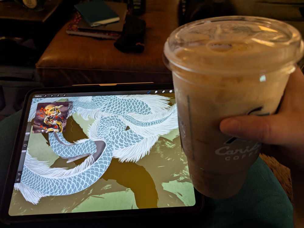 A person's hand holds a massive thing of coffee in front of an iPad screen with a WIP of a koi dragon 