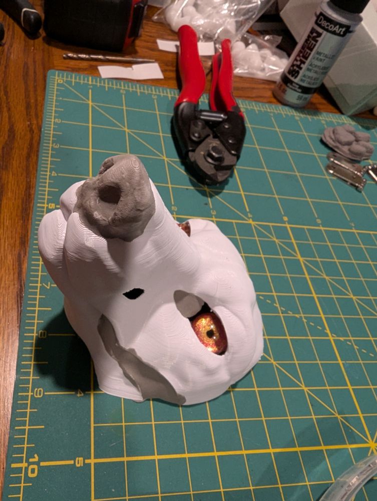 A white 3d printed canine head base with gold eyes gives the viewer some serious side eye