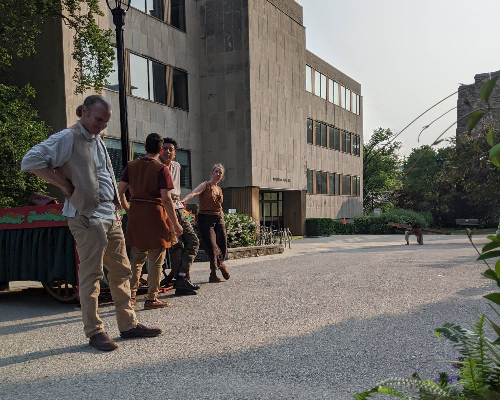 Four layabout soldiers stand on the left. Far down the road on the right, Jesus kneels beneath his cross. The air is hazy with wildfire smoke