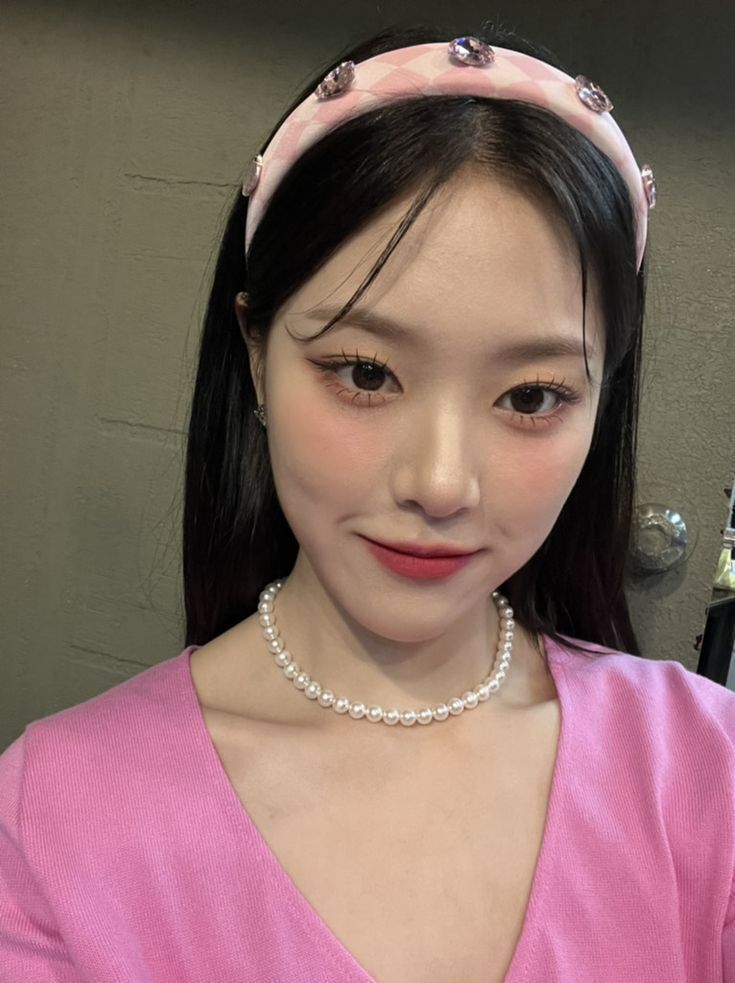 hyunjin in pink shirt and a pink headband. she is smiling
