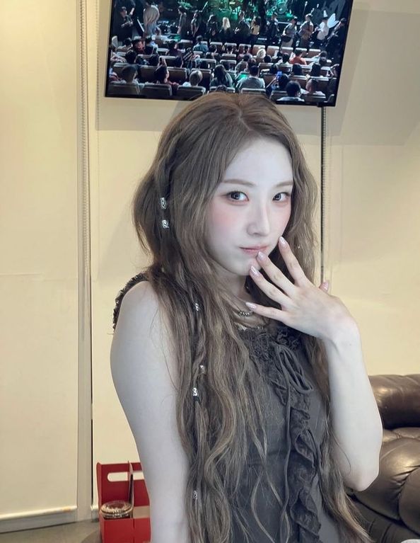 haseul in brown shirt. she has her hand on her face