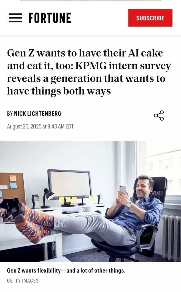 Picture of a person in an office with feet up and using a cellphone, with a salt and pepper beard, skinny jeans, and "funky" socks.