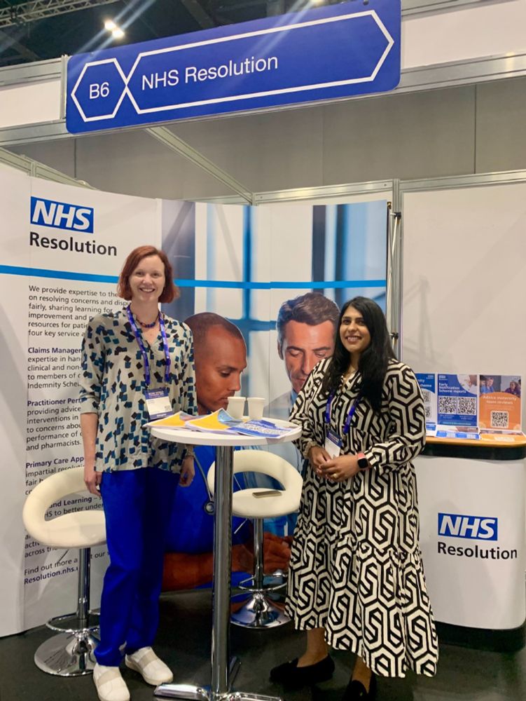 Two NHS Resolution colleagues at our exhibition stand with a banner and some leaflets.