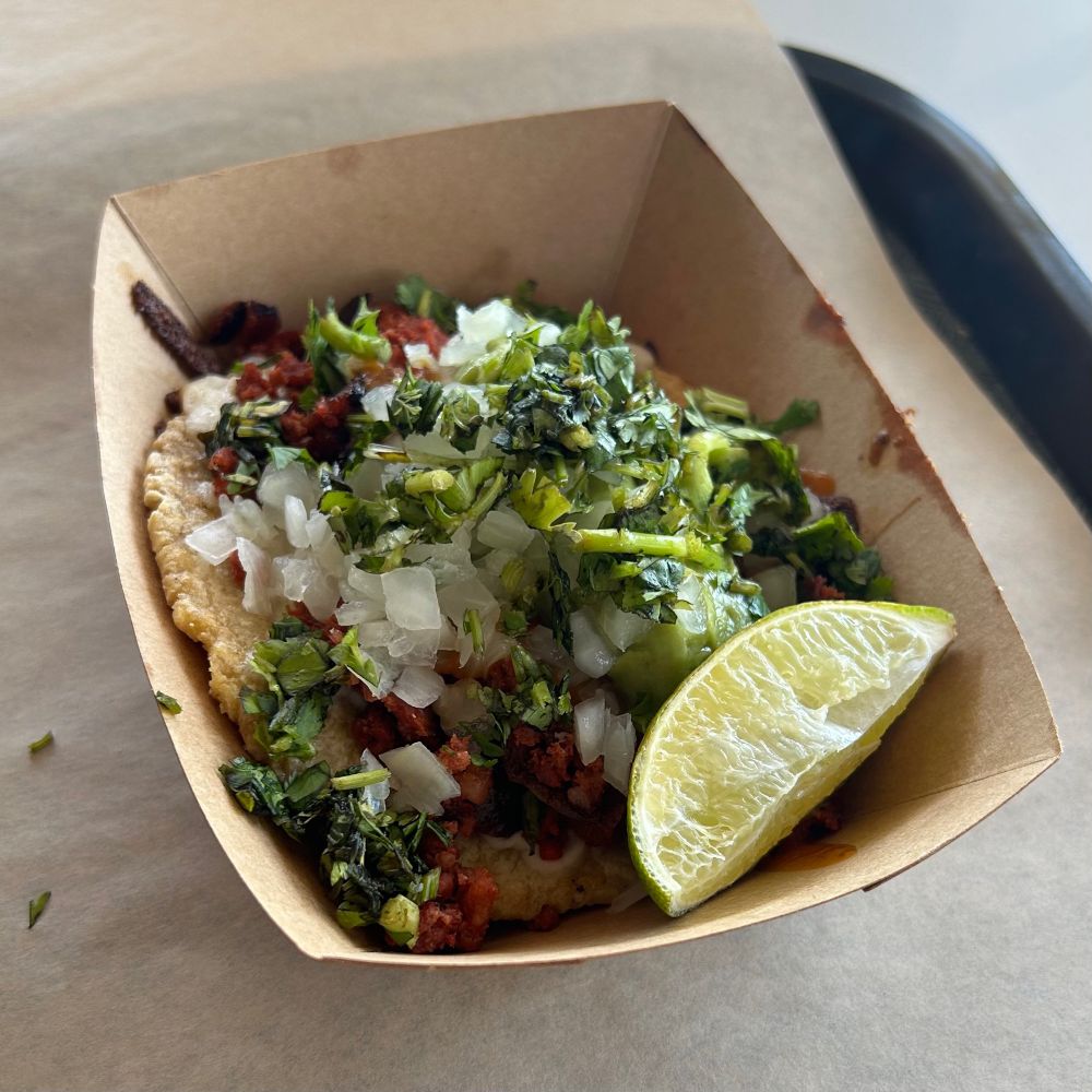 vividly red pork on a corn tortilla, mounded with glistening fresh onion and coriander salad and guacamole, with a lime wedge on the side