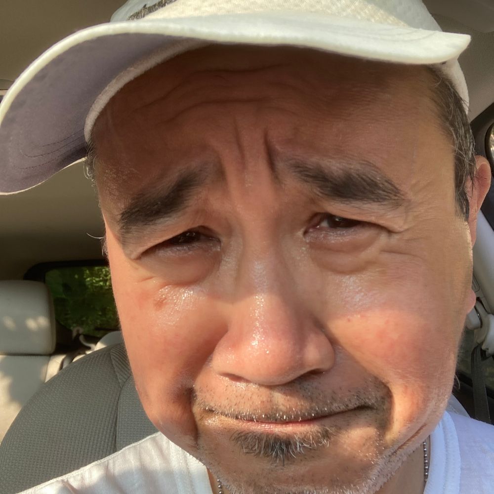 Selfie of Filipino dude in his car and squinting in the morning sun.