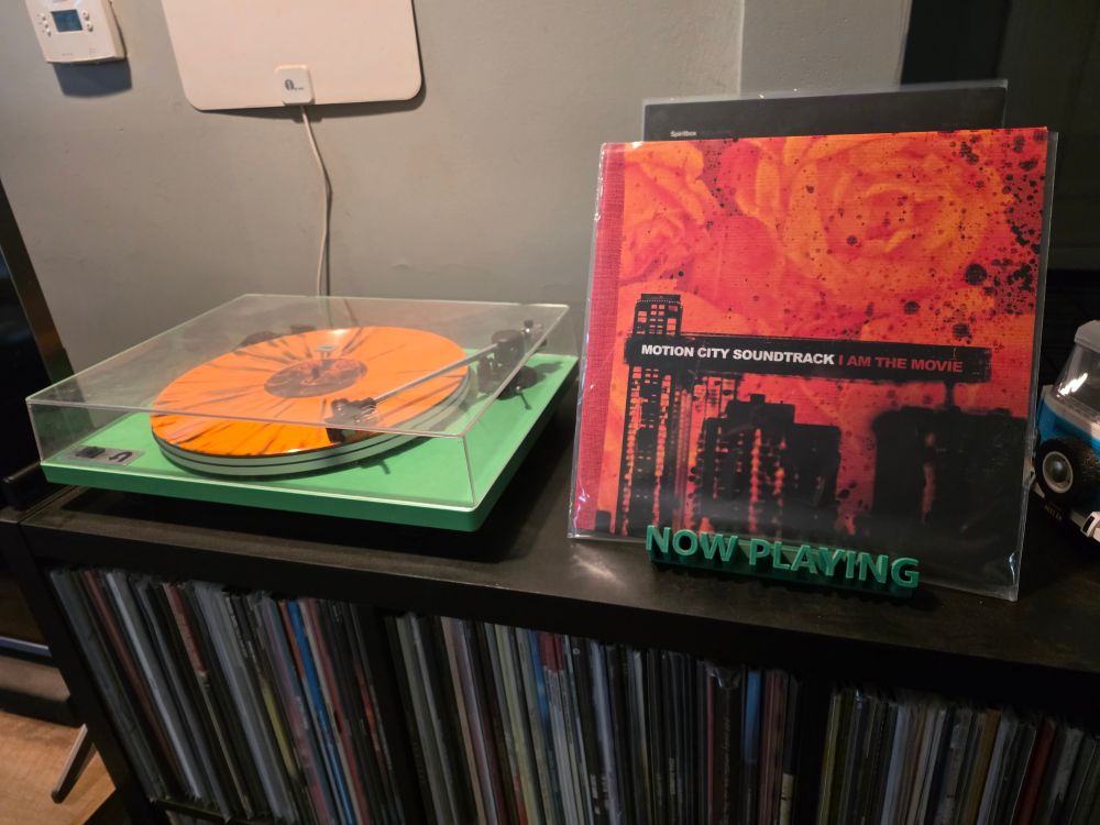 The album "I Am The Movie" by Motion City Soundtrack plays on a green turntable.