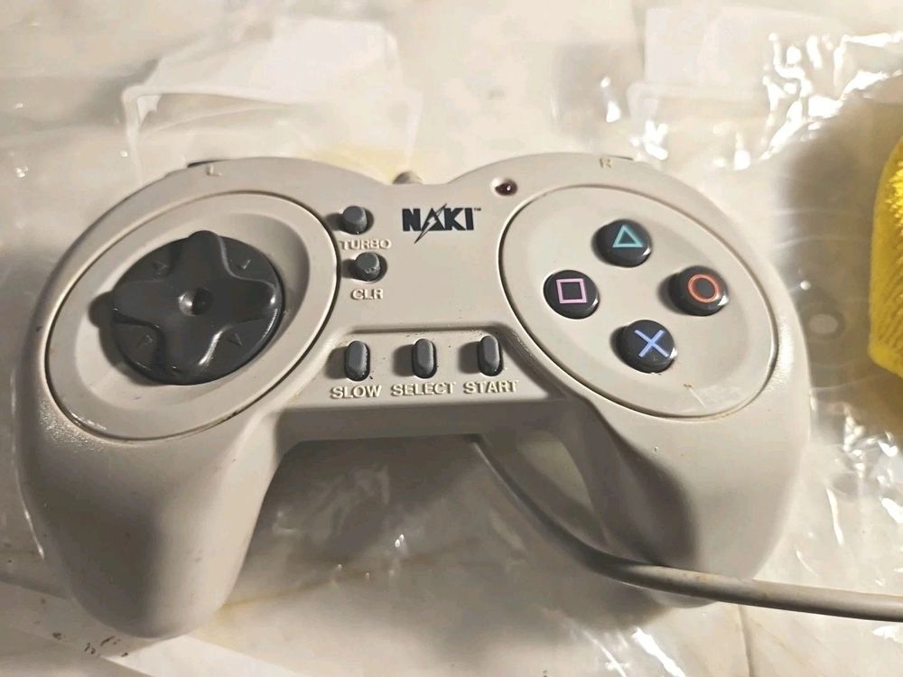 A third party PlayStation controller with the brand "NAKI" on it. It has extra buttons for "TURBO", "CLR" and "SLOW", as well as small unlit LED. It does not have analog sticks.