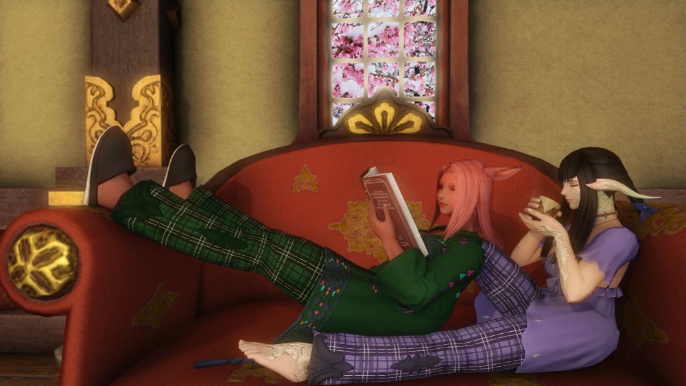 Bris and Yugiri lounge on a chair inside.  Yugiri is in a purple gown-style top and purple plaid pants and sipping tea..  Bris is in a green housecoat and green plaid pants, holding a book in her left hand.  Yugiri's right leg is raised and bent at the knee where her foot would be flat on the couch, but this is obscured by Bris who is leaning against that leg.  Bris's legs are both propped on the armrest of the chair.  Out the window behind them is a sakura tree, completely covered in heavy snow.