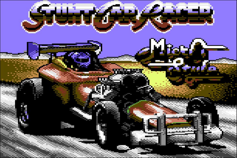 The glorious loading screen for "Stunt Car Racer" on the C64. Blue sky (light), desert background, grey tarmac. The logos for the game and "Micro Style" are depicted. And a flippin' cool-looking red drag / race car with a massive engine mounted centre FWD. Genius.
