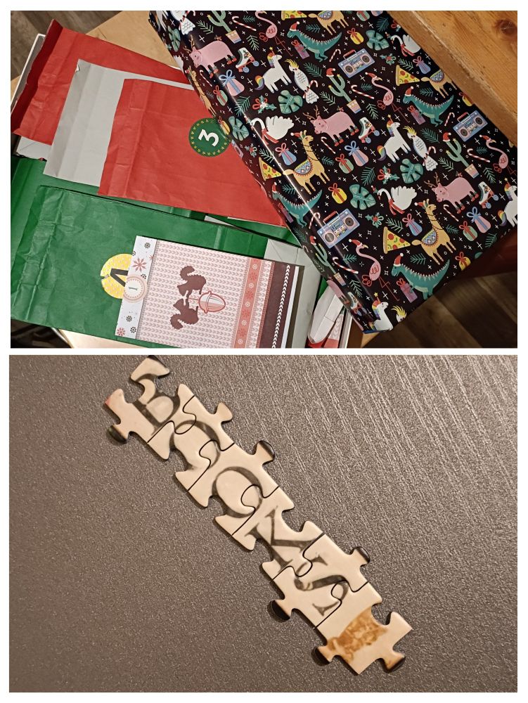 Eine Puzzlebox in Weihnachtsdeko mit noch verschlossenen, nummerierten Tütchen und sechs Puzzleteile mit dem Wort "Books".