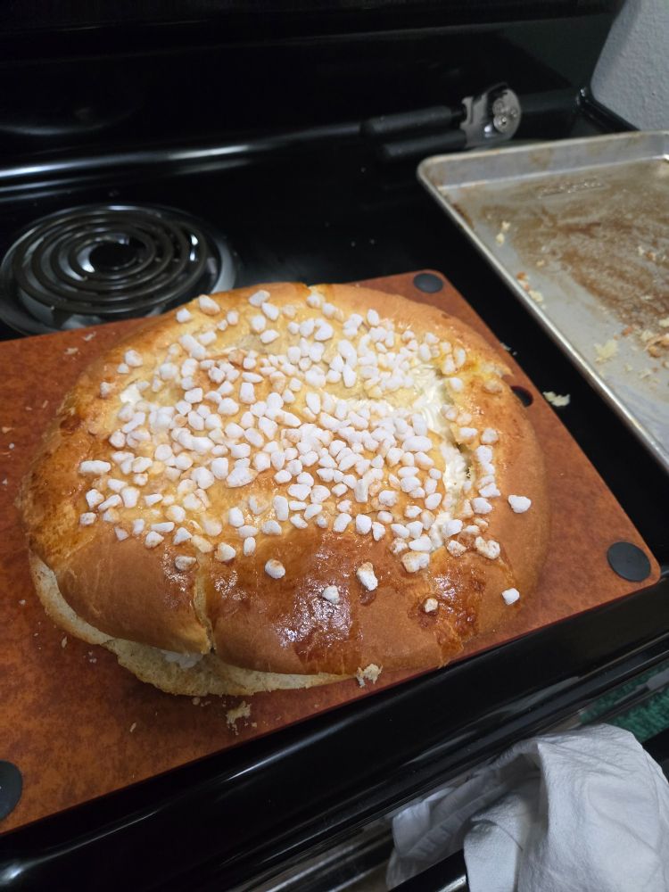 Some brioche bread with pearl sugar on the top, buttercream frosting in the middle where the bread has been cut in half.