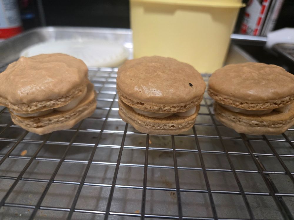 A different angle of the macaorons. Decently baked and assembled macarons. Light brown coffee flavored cookies with pale brown caramel frosting.