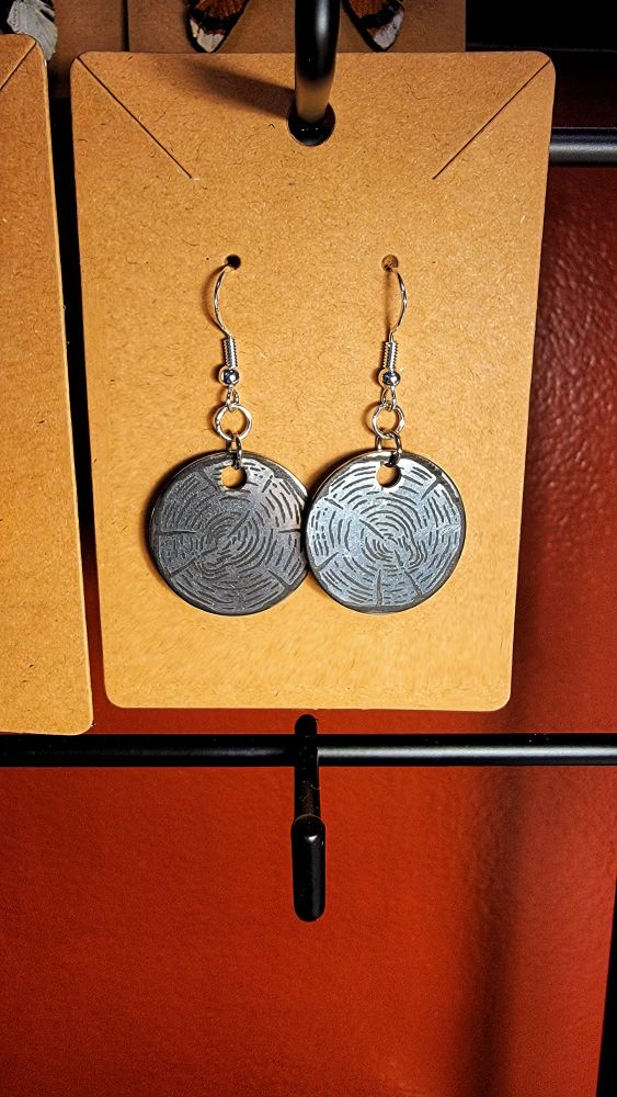 A photo of earrings that have been engraved to look like tree cookies.