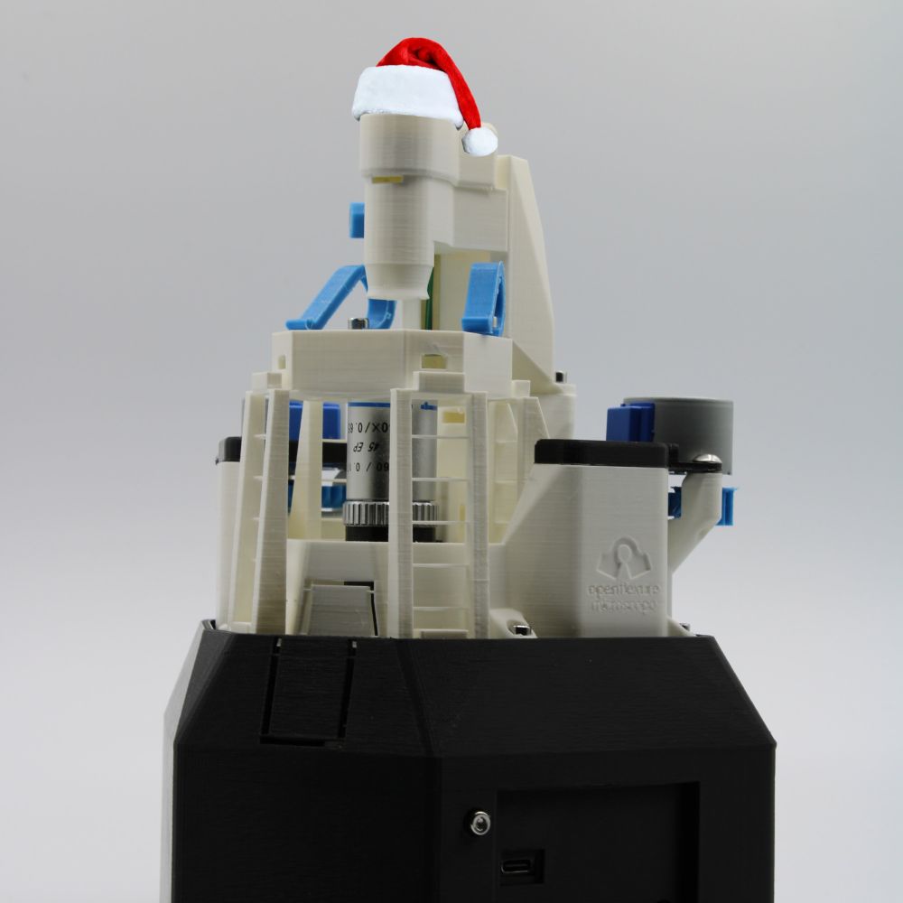 An OpenFlexure Microscope wearing a Santa hat.