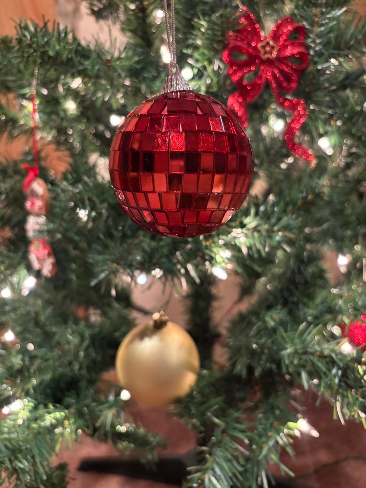 Red mirrorball Christmas ornament in front of a Christmas tree