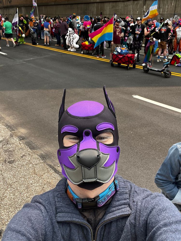 Féilim stands in front of a group of fur suiters and pups in the Pittsburgh Pride parade