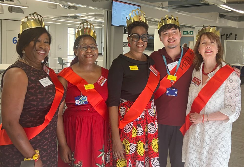 Group photo of five presenters at the launch of a new video series. They each wear a red sash in celebration of Red 4 Research Day