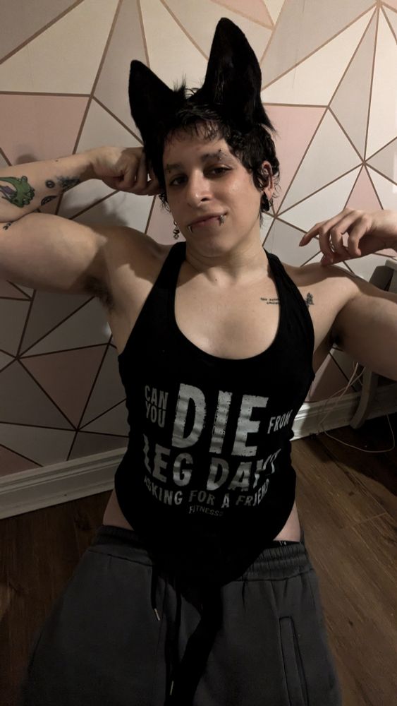 A photo of Sable kneeling before you, wearing grey sweat pants, a tank top and black dog ears.