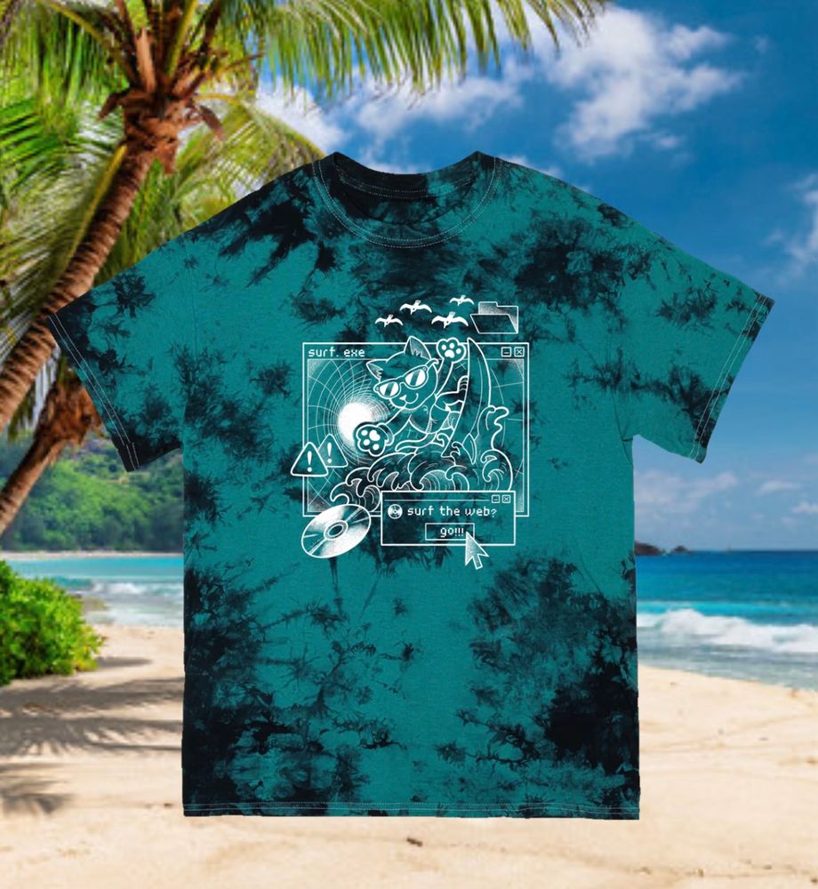 black and teal tie-dye tshirt with design of cat surfing through cyberspace, over a background of a stock image tropical beach