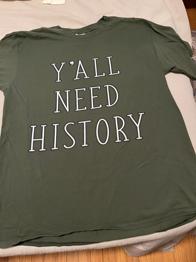 Green tshirt with Y’all Need History in white lettering