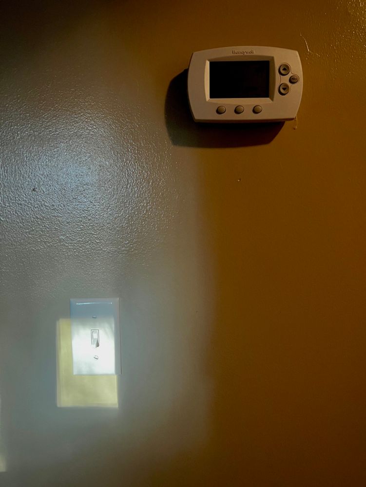 Light pattern on a wall that almost surrounds a light switch plate, but is off-center to the south west, so to speak. A naturally-occurring light pattern that mimics the frustration many have with html and css..