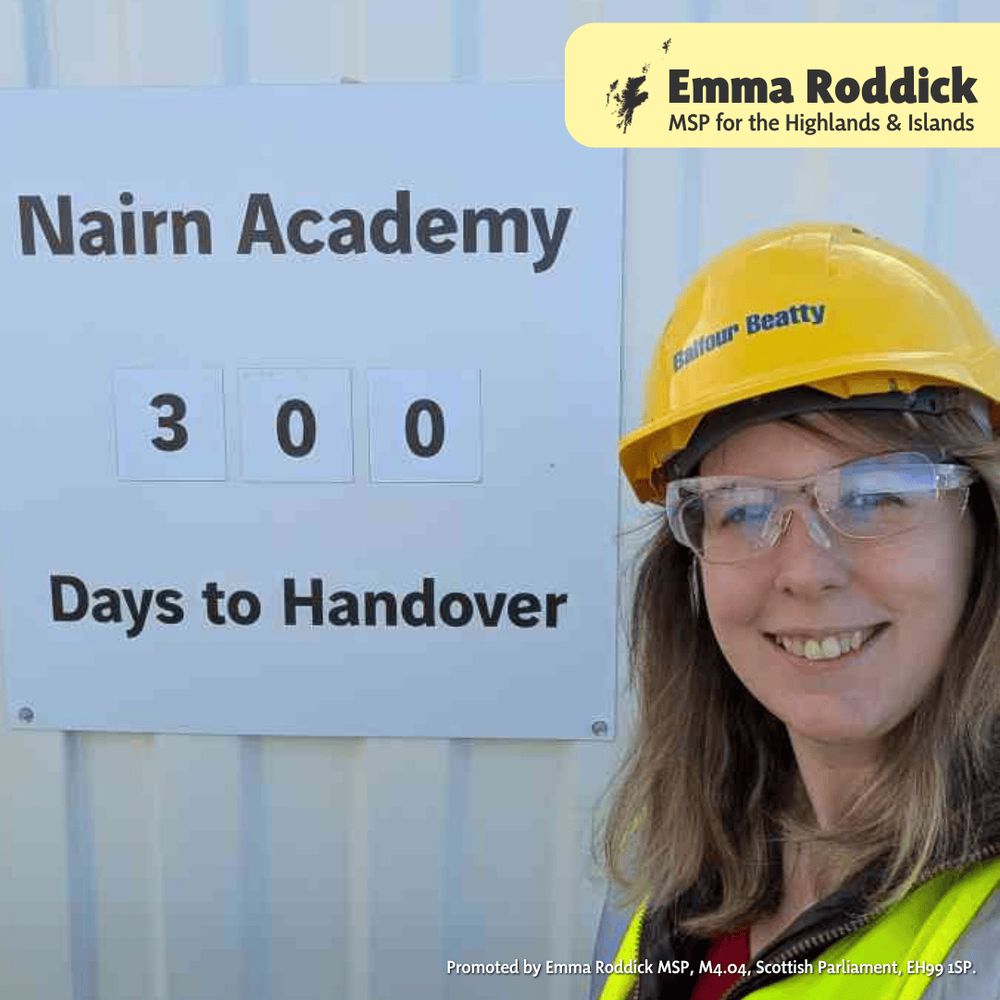 Emma takes a selfie in her yellow "Balfour Beatty" hat and hi-vis vest, next to a sign that says "Nairn Academy, 300 Days to Handover" - the numbers are swappable.