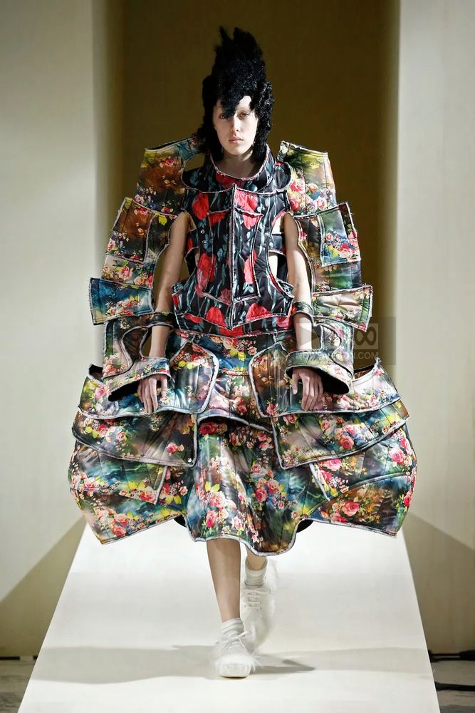 A model wearing a sculptural creation from Comme Des Garçon's Fall Winter 2016 collection. Many separated flower-printed pieces are sewn together and look like a modern reinvention of a medieval armor.