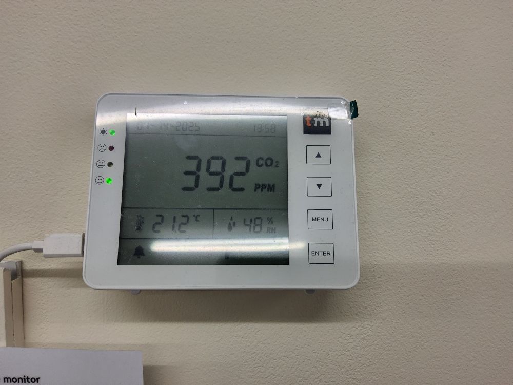 A CO2 meter mounted on a wall that reads 392 parts per million, 48% humidity and 21.2 degree celcius in tempreture.