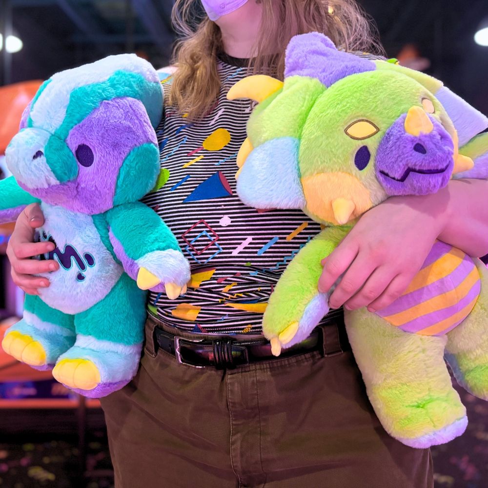 photo of a person holding Rawrcade characters Cade and Fizz plush at an arcade