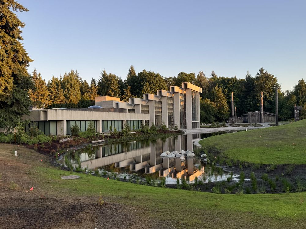 The newly finished and renewed Great Hall and MOA grounds and pond from a distance at sunset. The Haida Village is in the distance.
