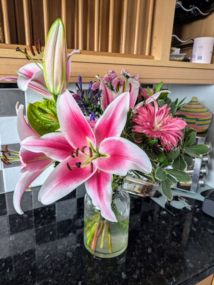 Vase of flowers dominated by large pink lillies 