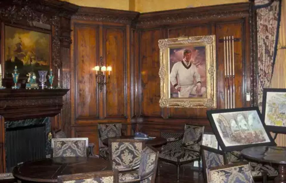 A wood paneled room with sconces and a portrait of trump on The wall.