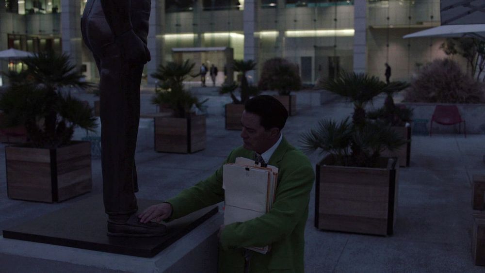 Scene from Twin Peaks The Return where Dougie Jones touches shoes of a statue outside of his office like he recalls something from his past.
