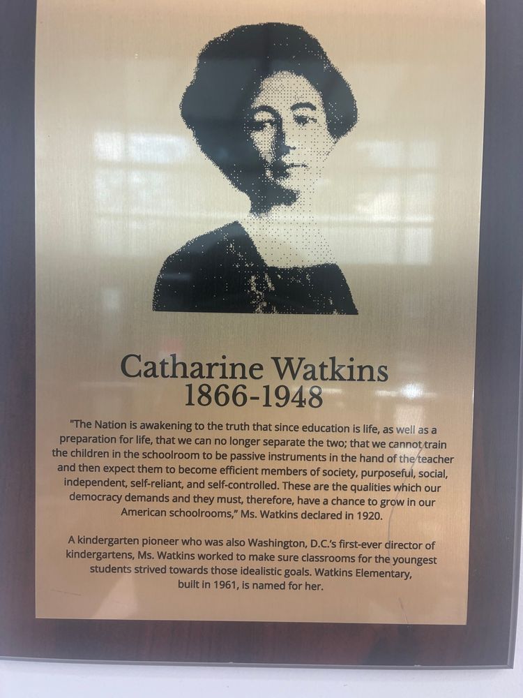 Image and inscription of Catharine Watkins (1866-1948).

"The Nation is awakening to the truth that since education is life, as well as a preparation for life, that we can no longer separate the two; that we cannot train the children in the schoolroom to be passive instruments in the hand of the teacher and then expect them to become efficient members of society, purposeful, social, independent, self-reliant, and self-controlled. These are the qualities which our democracy demands and they must, therefore, have a chance to grow in our American schoolrooms," Ms. Watkins declared in 1920.

A kindergarten pioneer who was also Washington, D.C.'s first-ever director of kindergartens, Ms. Watkins worked to make sure classrooms for the youngest students strived towards those idealistic goals. Watkins Elementary, built in 1961, is named for her.