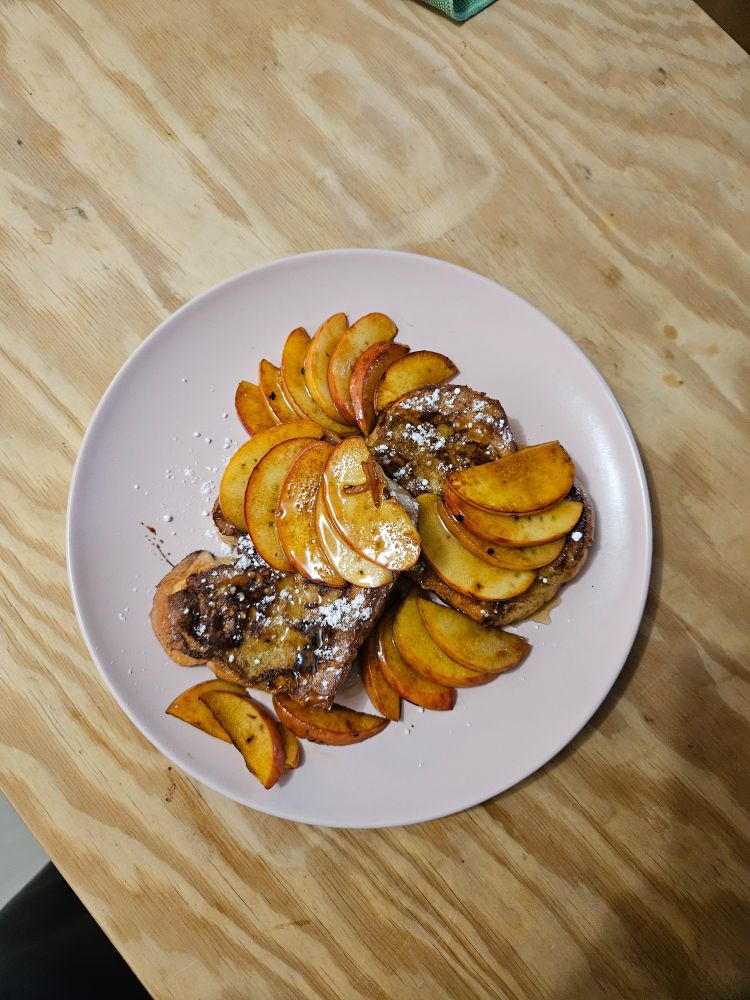 Photo de mon petit déjeuner, brioche perdue avec des demi tranches de pommes revenues dans du beurre. Le tout présenté dans une assiette rose pastel.