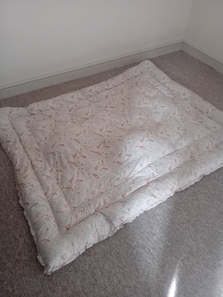 An eiderdown with a faded pale blue, yellow, and red paisley pattern.