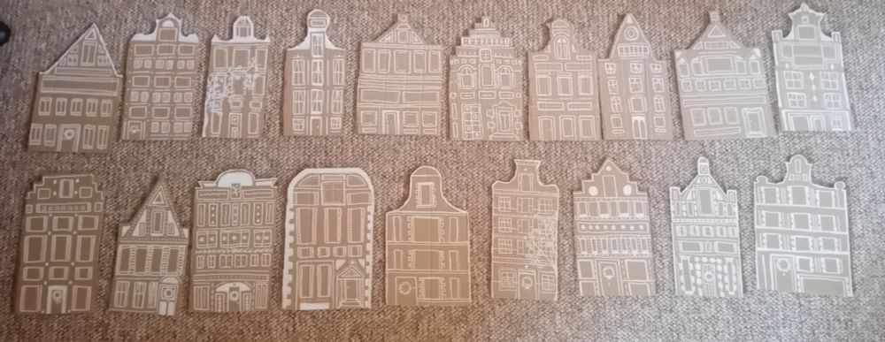 19 pieces of brown cardboard cut out to look like canal side houses in Amsterdam. They've been painted so they look like gingerbread houses with white icing. 