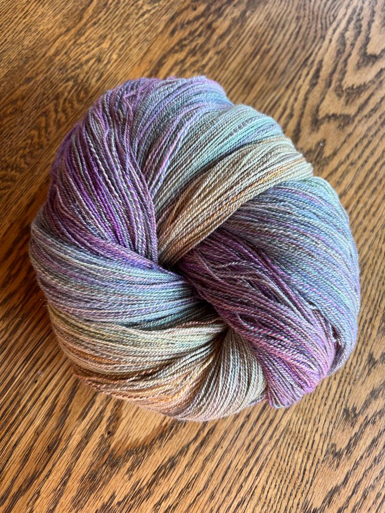 4 hanks of lightly variegated yarn in pastel purples, blues, greens, and yellows, twisted together into a knot