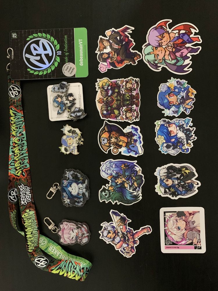 An image with a variety of swag from Combo Breaker 2025! Includes a custom Combo Breaker competitor badge, Elphelt and Dizzy keychains and a Dizzy enamel pin from @wavechan.bsky.social, a 3-pin set from @oxcoxa.bsky.social, a 5 pack of stickers for Elphelt, Dizzy, May, Potemkin and Sharon/Slayer from @cinamuffins.bsky.social, an Elphelt album cover and Dizzy sticker from @radiostarkiller.bsky.social, a Dizzy sticker from @microcake.bsky.social, a Dizzy sticker from @spacedey.bsky.social, and a Lilith and Morrigan duo sticker from @yungkhan.bsky.social!