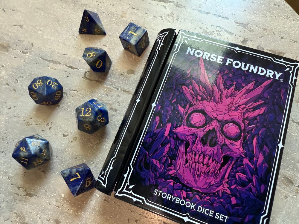 TTRPG dice set in blue with tin case shaped like a book. 