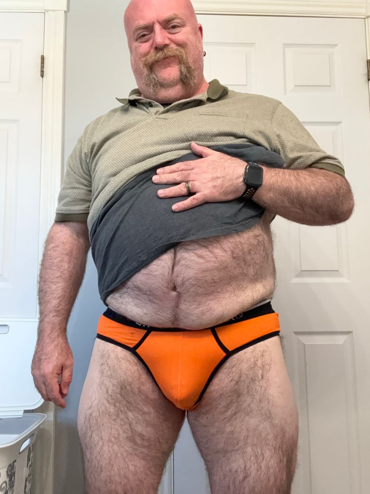 Man in greet tshirt wearing orange briefs