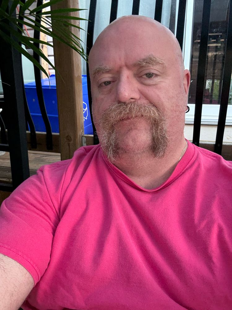 Man with handlebar moustache in a pink t-shirt. 