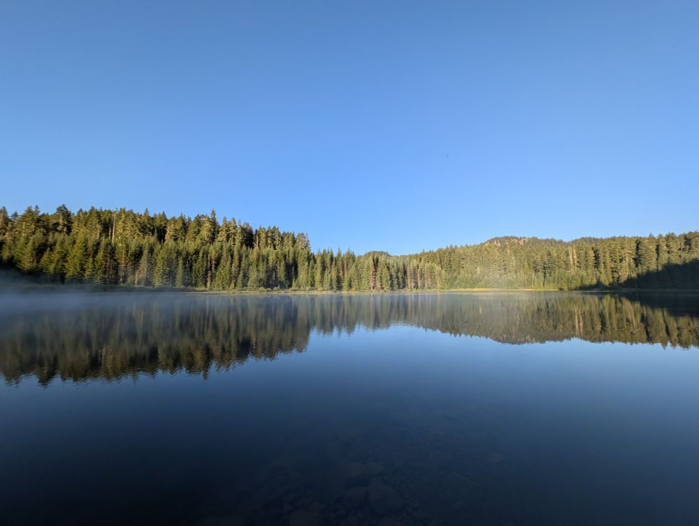 Hemlock Lake, smooth as glass, reflecting the trees and blue aky