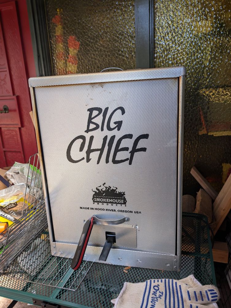 A big chief smoker in which trout are hanging and bathing in alder and apple smoke 