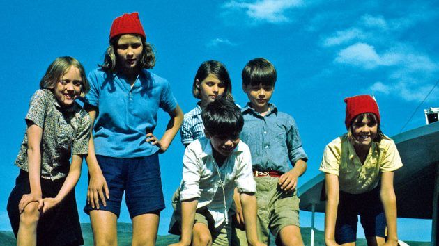 A still from the movie Swallows and Amazons (the original version, which is good, not the newer one, which is crap). It shows 6 kids, two of them in red hats. The red hatted kids are the Amazons, and the others are the Swallows. Their maritime disagreements are the focus of the story.