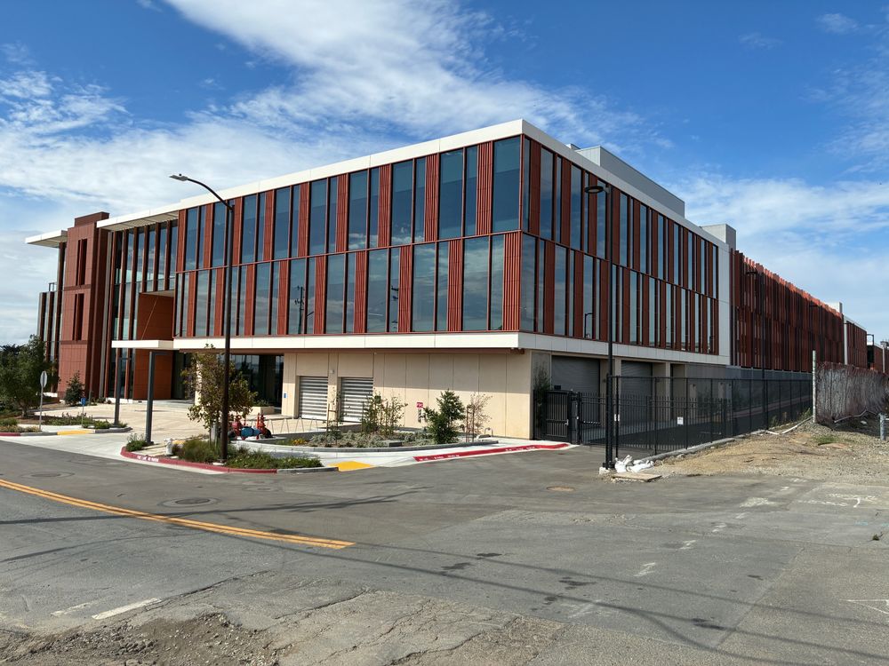 601 Bancroft, a massive new 3-story structure with chocolate walls and big glass reflecting an excellent blue sky with streaky high clouds