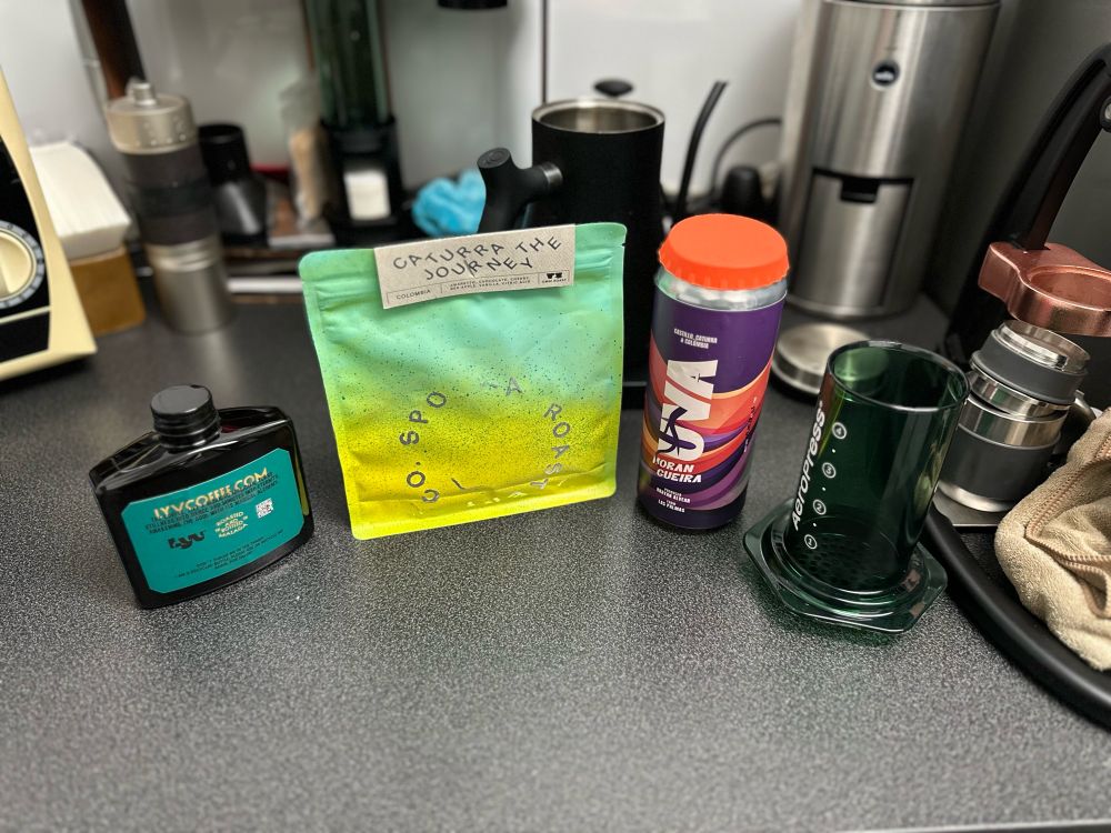 El alijo recogido del festival del café: tres variedades de Caturra con distintos procesos de lavado. Uno de ellos con notas fuertes a uva y otro a almendras. Un Aeropress verde. Y de fondo, toda la mierda que ya tenía jaja