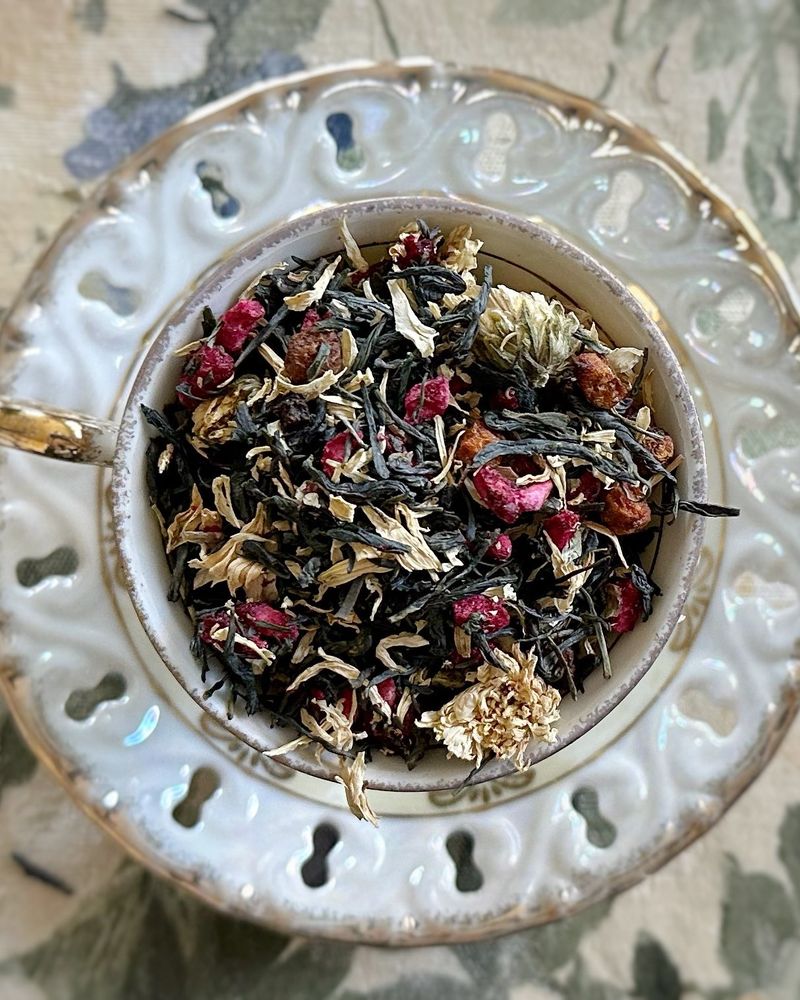 Teacup full of green tea, flowers, and pink fruit