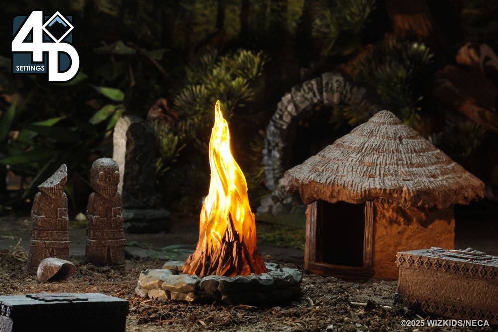 Picture of the miniatures of a roaring bonfire in the center with a small hut to the right and a pair of stone statues to the left, with jungle stretching into the background.